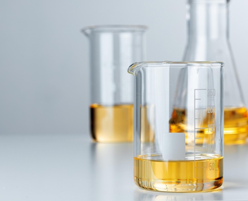 Three glass beakers filled with a yellow chemical liquid.