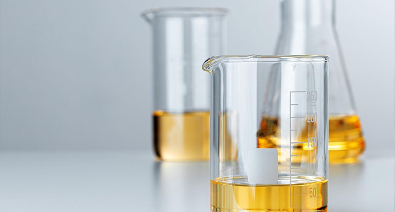 Three glass beakers filled with a yellow chemical liquid.