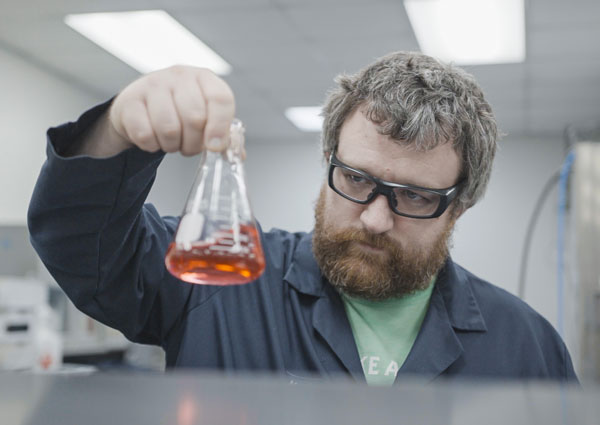 HEM Group Sustainability of product being tested by man with red chemical in beaker